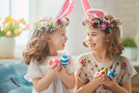 Cute little children wearing bunny ears on Easter day. Girls with painted eggs.の写真素材