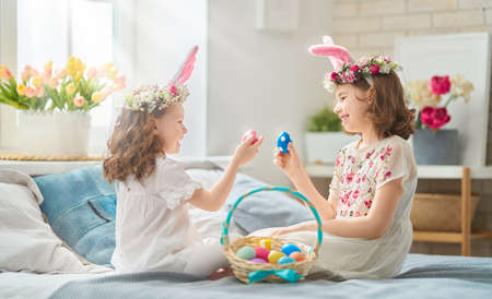 Cute little children wearing bunny ears on Easter day. Girls with painted eggs.の写真素材