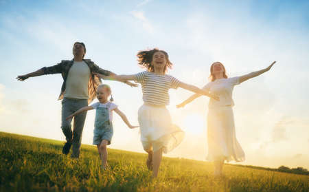 Happy family on summer walk! Mother, father and daughters walking in the Park and enjoying the beautiful nature.の写真素材