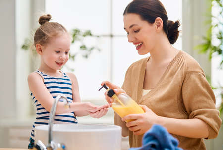 A cute little girl and her mother are washing their hands.の写真素材