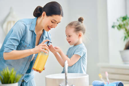 A cute little girl and her mother are washing their hands.