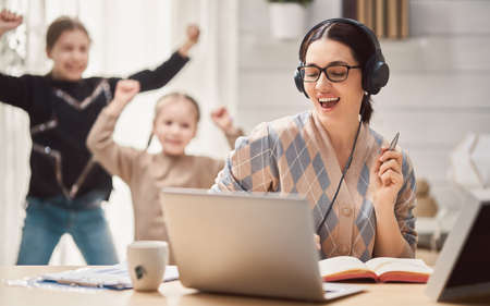 Young mother with children working on the computer. Family at home. Remote work.