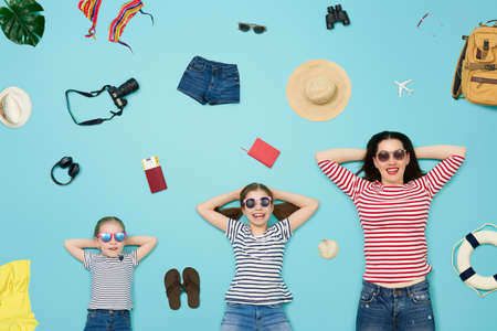 Happy family preparing for the journey. Mom and daughters on color teal background.の写真素材
