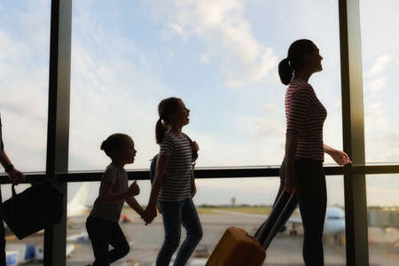 Happy family with children at the airport. Parents and their children look out the window at the plane.の写真素材