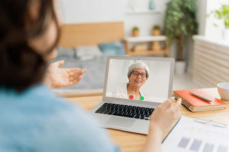 Young woman is using laptop pc for remote conversation with mother. Funny girl having fun staying at home.の写真素材