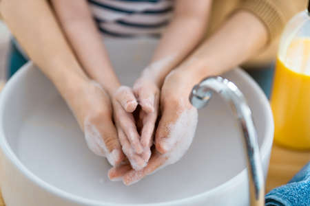 Kid and adult are washing their hands. Protection against infections and viruses. Close up.の写真素材
