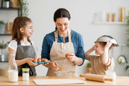 Happy loving family are preparing bakery together. Mother and children daughters girls are cooking...