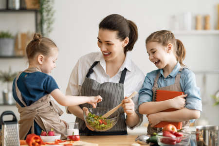 Healthy food at home. Happy family in the kitchen. Mother and children daughters are preparing vegetables.の写真素材