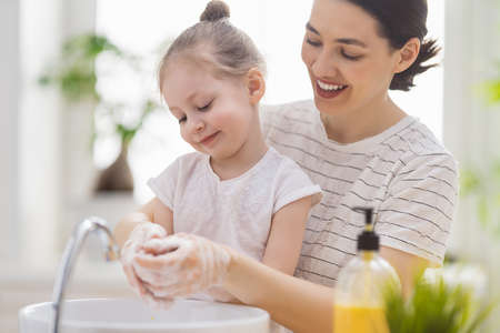 A cute little girl and her mother are washing their hands. Protection against infections and viruses.の写真素材