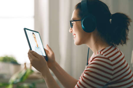 Young woman is using tablet pc for remote conversation with friends. Funny girl having fun staying at home.の写真素材