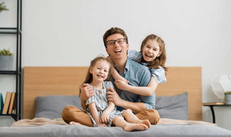 Happy loving family. Daddy and his daughters children girls playing together. Father's day concept.の写真素材