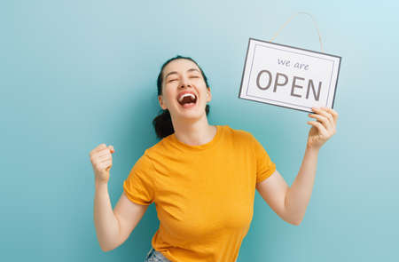 Small business owner smiling and holding the sign for the reopening of the place after the quarantineの写真素材