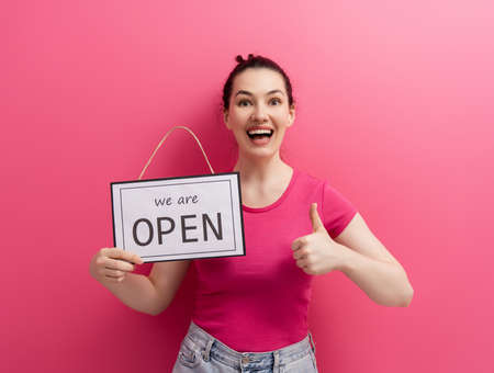 Small business owner smiling and holding the sign for the reopening of the place after the quarantineの写真素材
