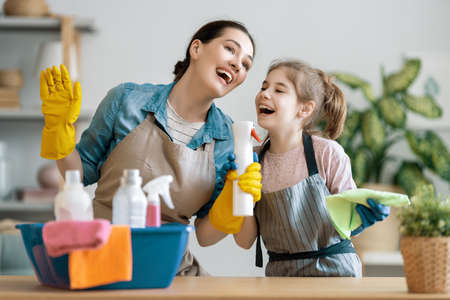 Happy family at home. Mother and daughter doing the cleaning in the house. A young woman and child girl are dusting. Cute little helper.の写真素材