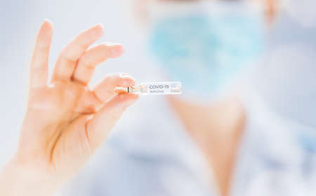 Medical doctor or laborant holding tube with anti Coronavirus vaccine. Concept of Covid-19 treatment...
