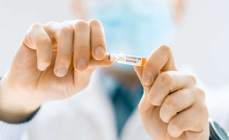 Medical doctor or laborant holding tube with anti Coronavirus vaccine. Concept of Covid-19 treatment and prevention.の写真素材