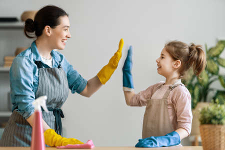 Happy family at home. Mother and daughter doing the cleaning in the house. A young woman and child...