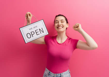 Small business owner smiling and holding the sign for the reopening of the place after the quarantine due to covid-19.の写真素材