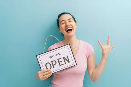 Small business owner smiling and holding the sign for the reopening of the place after the quarantine due to covid-19.の写真素材