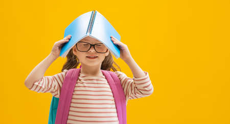 Back to school and happy time! Cute industrious child on color paper wall background. Kid with...
