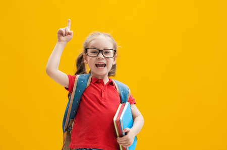 Back to school and happy time! Cute industrious child on color paper wall background. Kid with...