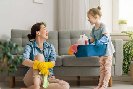 Happy family at home. Mother and daughter doing the cleaning in the house. A young woman and child girl are dusting. Cute little helper.の写真素材