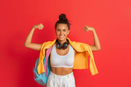 Happy emotional young woman in sporty clothes laughing on bright red backgroundの写真素材