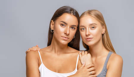 Portrait of two young women standing together and hugging.