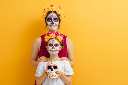 Adorable zombies in flower wreaths posing on yellow background. Happy family with Halloween creative...