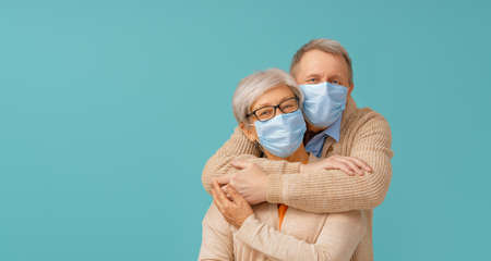 Senior couple wearing facemask during coronavirus and flu outbreak. Virus and illness protection, home quarantine. COVID-2019. Taking on masks.の写真素材