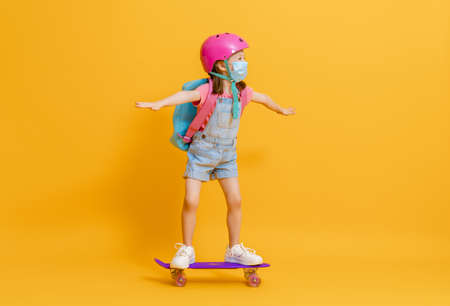 Childhood and happy time! Cute child with skateboard on color paper wall background. Kid with...