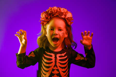 Happy Halloween! Cute little witch at party in colorful lighting.