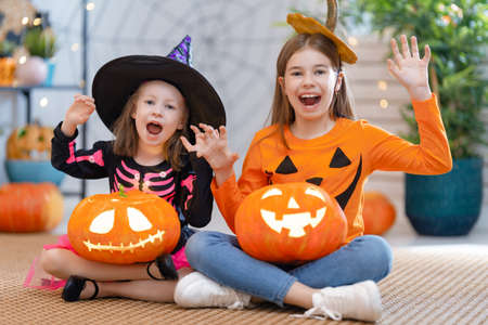 Cute little children girls with carving pumpkin. Happy family preparing for Halloween. Funny kids at home.の写真素材