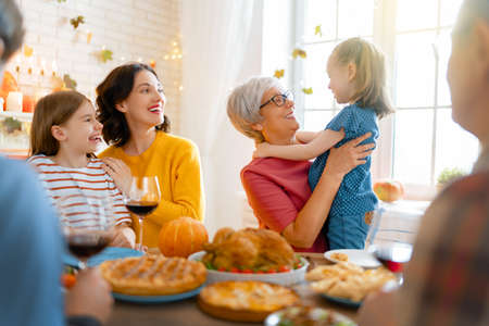 Happy Thanksgiving Day! Autumn feast. Family sitting at the table and celebrating holiday. Grandparents, mother, father and children. Traditional dinner.の写真素材