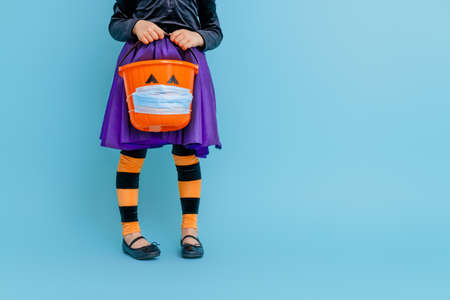 Happy Halloween! Little kid with a basket for sweets  wearing face mask protecting from COVID-19.の写真素材