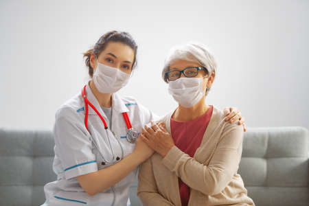 Doctor and senior woman wearing facemasks during coronavirus and flu outbreak. Virus protection. COVID-2019. Taking on masks.の写真素材