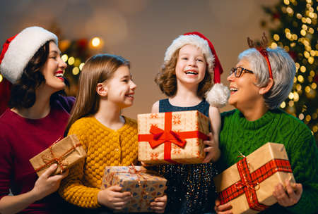 Merry Christmas and Happy Holidays! Cheerful kids presenting gifts to mom and granny. Parents and...