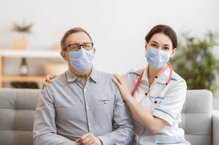 Doctor and senior man wearing facemasks during coronavirus and flu outbreak. Virus and illness protection, home quarantine. COVID-2019の写真素材