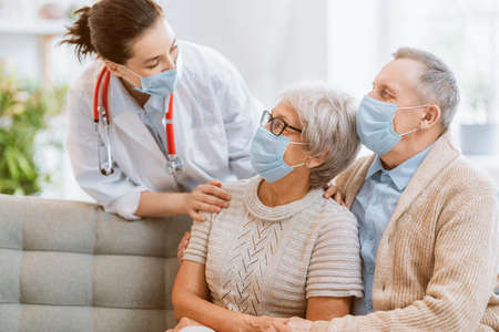 Doctor and senior couple wearing facemasks during coronavirus and flu outbreak. Virus protection, home quarantine. COVID-2019. Taking on masks.の写真素材