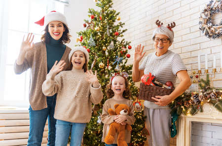 Merry Christmas and Happy Holidays! Granny, mom and daughters near the tree indoors. The morning...