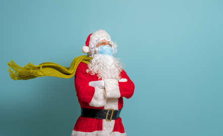 Merry Christmas and Happy Holidays! Santa Claus in face mask on bright color background. Covid-2019の写真素材