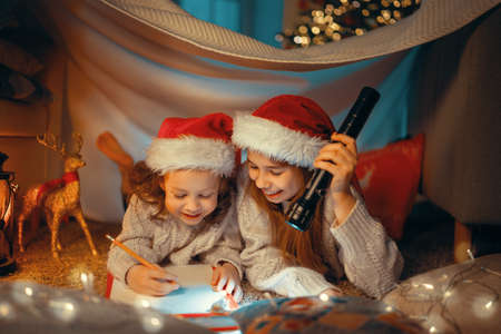 Merry Christmas and Happy Holidays! Cute little children girls are writing the letter to Santa Claus...
