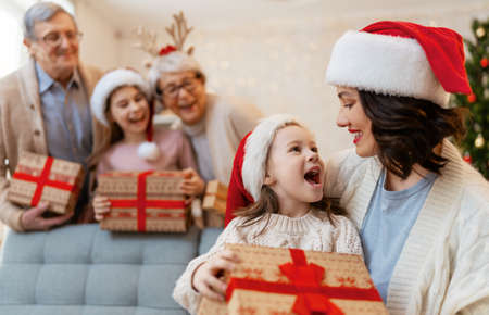 Merry Christmas and Happy Holidays! Grandma, grandpa, mum and children exchanging gifts. Parents and...
