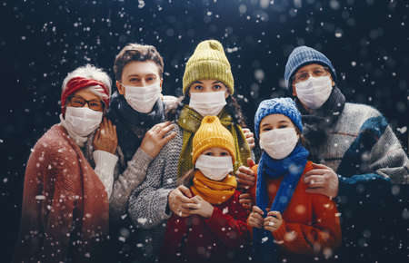 Merry Christmas and Happy Holidays! Portrait of loving family on dark snowy background. People wearing facemasks.の写真素材