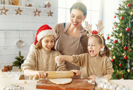 Merry Christmas and Happy Holidays. Family preparation holiday food. Mother and daughters cooking cookies.の写真素材