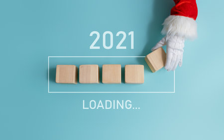 Loading new year 2020 to 2021 with hand of Santa Claus putting wood cube in progress bar.の写真素材
