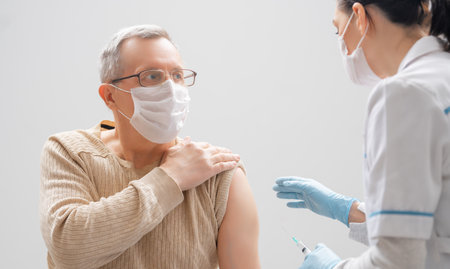 Doctor giving a senior man a vaccination. Virus protection. COVID-2019.の写真素材