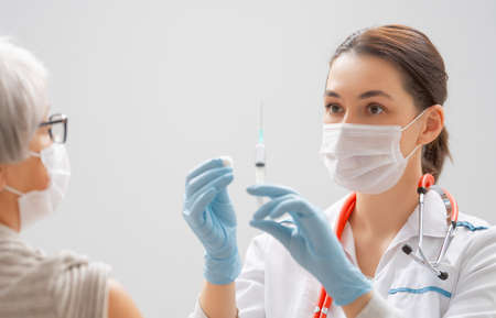 Doctor giving a senior woman a vaccination. Virus protection. COVID-2019.の写真素材