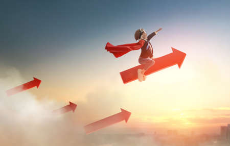 Superhero businessman child on sunset background. The concept of success, leadership and victory in education.の写真素材