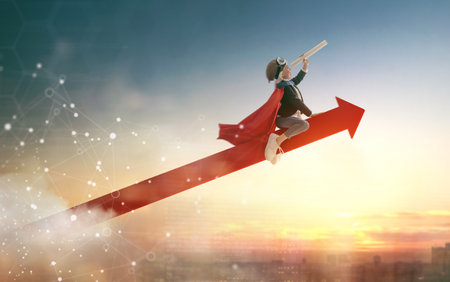 Superhero businessman child on sunset background. The concept of success, leadership and victory in...